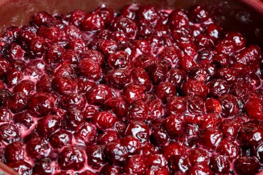 Ahşap bir masanın üzerindeki tencerede nefis kiraz reçeli, yakın plan, üst manzara. Yaz hazırlığı ve kış için böğürtlenlerin korunması, ev yemekleri