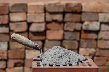 Kuru çimento ya da harç. İnşaat alanındaki kırmızı tuğlada çimento tozu ve mala yakın.