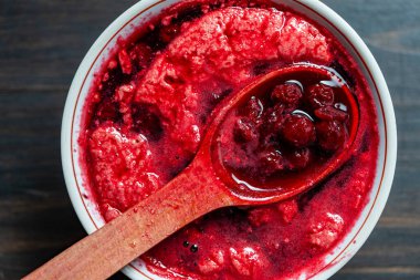 Tahta kaşıkla beyaz bir kasede vişne reçeli yapmak için taze toplanmış kirazlı şekeri hazırlıyorum. Çilek reçeli, ev yemeği.