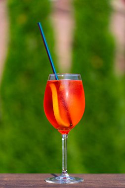 Aperol spritz kokteyli ve şarap kadehi, doğal bir arka plan. Klasik İtalyan aperatifi aperatif sprey kokteyli. Bir dilim portakallı. Kapatın. Yaz güneşli ferahlatıcı içecek