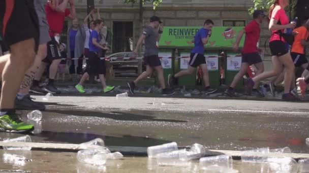 Одноразовые чашки и вода под ногами бегущих марафонцев — стоковое видео