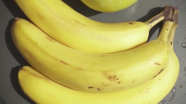 Медленное движение бананов и яблоко лежат на хлебном листе — стоковое видео