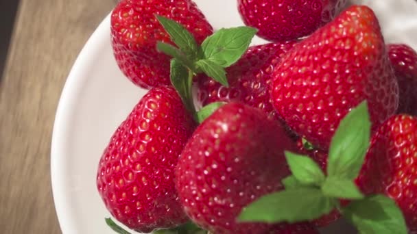 Erdbeere in Zeitlupe auf einem Teller und einem Glas mit natürlichem Saft — Stockvideo
