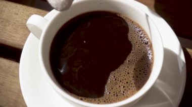 Beyaz porselen fincan sıcak bir içecek yavaş hareket ile ahşap bir masa üzerinde bir daire üzerinde