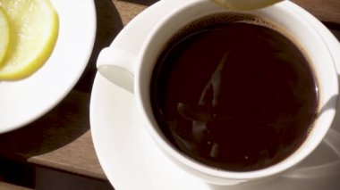 Beyaz porselen fincan sıcak bir içecek yavaş hareket ile ahşap bir masa üzerinde bir daire üzerinde