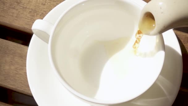 Tazza di porcellana bianca su un piattino su un tavolo di legno con una bevanda calda rallentatore — Video Stock