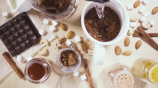 En una mesa de madera una taza blanca e ingredientes para cacao cámara lenta — Vídeos de Stock