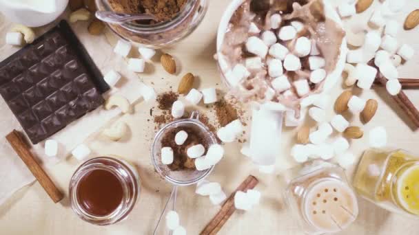 En una mesa de madera una taza blanca e ingredientes para cacao cámara lenta — Vídeos de Stock