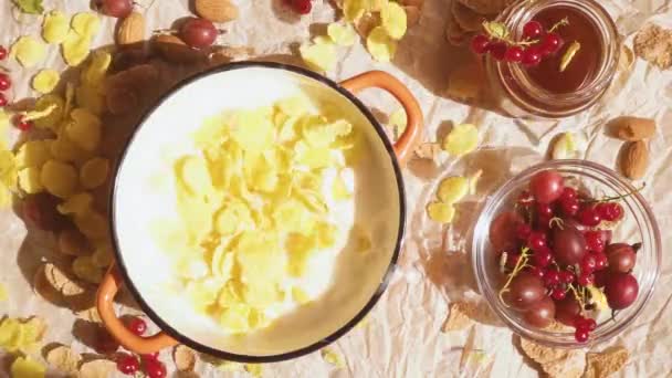 On a parchment paper a bowl with flakes and berries near the honey slow motion — Stock Video