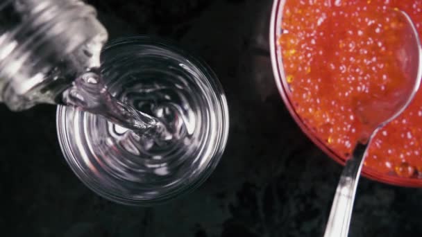 Медленное движение вылить водку в стакан на стол с икрой вид сверху — стоковое видео
