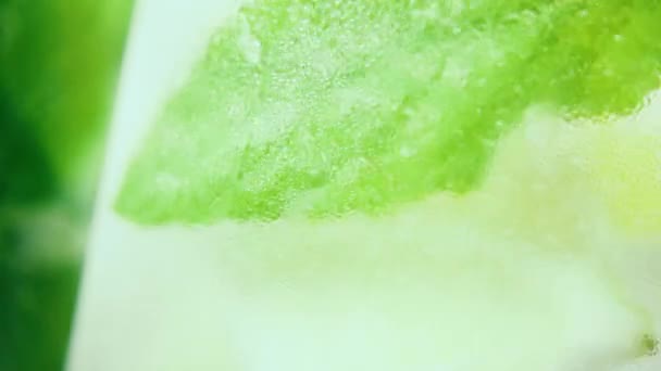 Slow motion in een beneveld glas draaien citroen limoen en mint close-up — Stockvideo