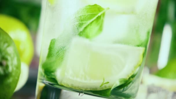 Lento movimiento en un vaso empañado con hielo y limón vierte agua — Vídeo de stock