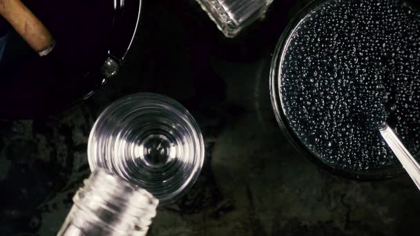 Slow motion vodka in a glass and caviar on a black background — Stock Video