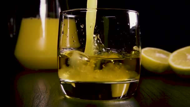 Wlać sok z zwolnionym tempie w silny napój alkoholowy w szklance — Wideo stockowe