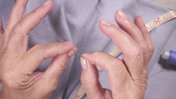 An elderly woman pulls a thread in a needle top view — Stock Video