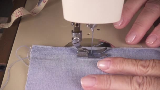 Las manos de las mujeres de cámara lenta cosen la tela en la máquina de coser — Vídeo de stock