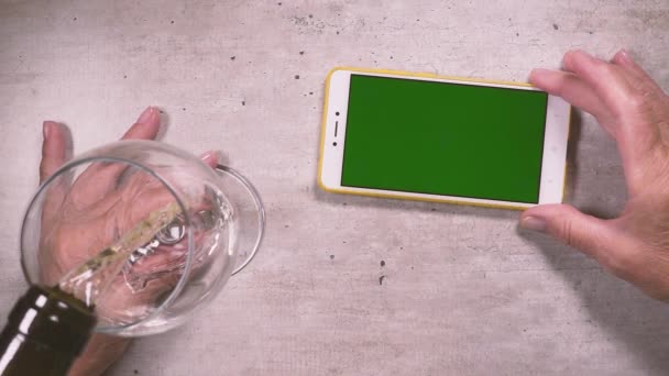 Zeitlupe in einem Glas Wein gießen und die Hand hält das Telefon von oben — Stockvideo