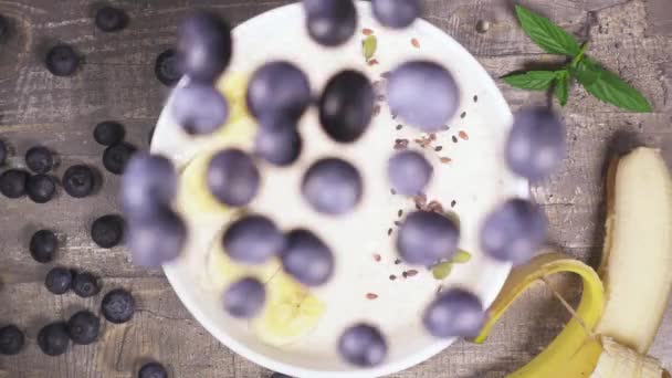 Slow motion in a bowl of fruit smoothie drop the berries top view — Stock Video