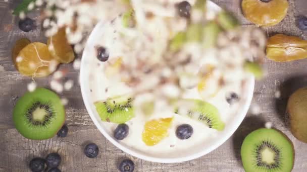 Slow motion in een kom fruit yoghurt smoothie drop het mengsel van sesam zaden bovenaanzicht — Stockvideo