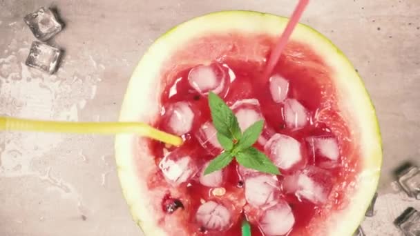 Långsam rörelse halv vattenmelon med sugrör och is roterar på vyn bordsskiva — Stockvideo