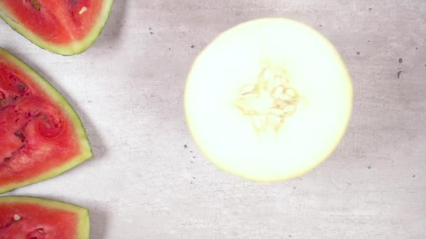 Slow motion halv melon rullar på bordet på skivor av vattenmelon ovanifrån — Stockvideo