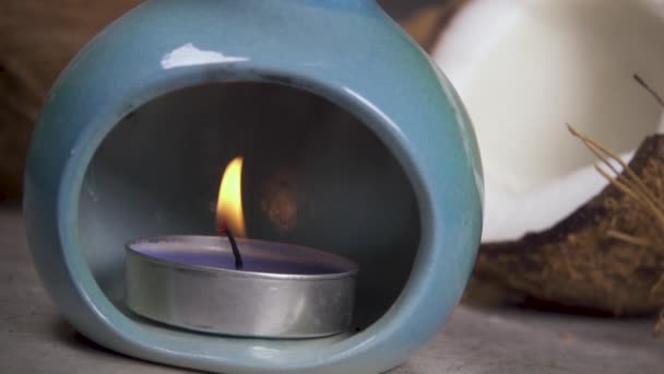 Candle in an aroma lamp on the background of the coconut — Stock Video