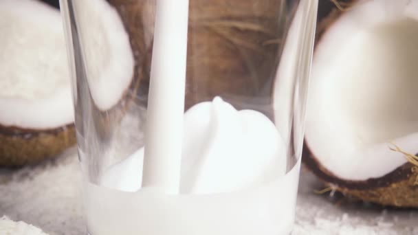 Leite de coco em câmera lenta e metades de coco na mesa — Vídeo de Stock