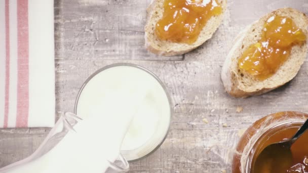 In Zeitlupe wird die Milch in ein Glas in der Nähe von Sandwich Draufsicht gegossen — Stockvideo