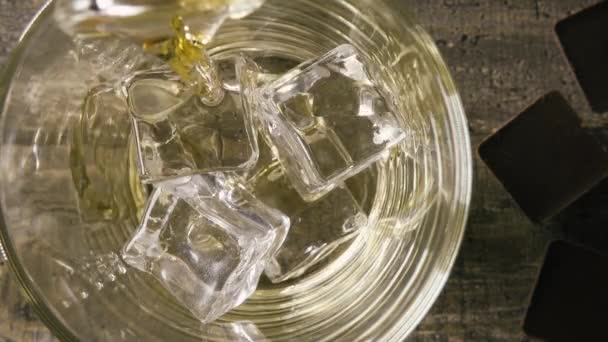 Slow motion in the glass with artificial ice pouring whisky top view — Stock Video