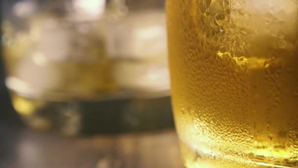 Slow motion druppels op het beneveld glas en in de achtergrond pour in een glas — Stockvideo