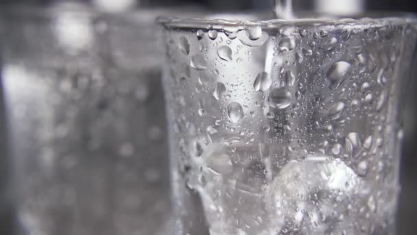 Lento movimiento en un vaso con gotas de agua para verter el vodka de cerca — Vídeo de stock