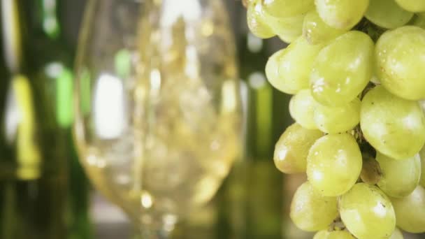 Slow motion bunch of grapes in the foreground and pour the wine into the glass — Stock Video