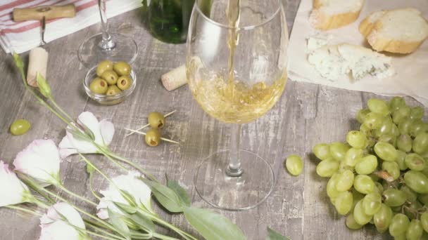 Zeitlupe gießen in ein Glas Wein zwischen Snacks und Blumen Draufsicht — Stockvideo