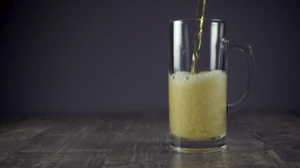 Slow motion vierte cerveza ligera en una taza sobre un fondo gris — Vídeo de stock