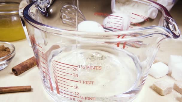 Slow motion glass measuring cup on the table near the ingredients — Stock Video