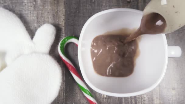 Slow motion chocolate caliente verter en una taza cerca de mitones vista superior — Vídeos de Stock