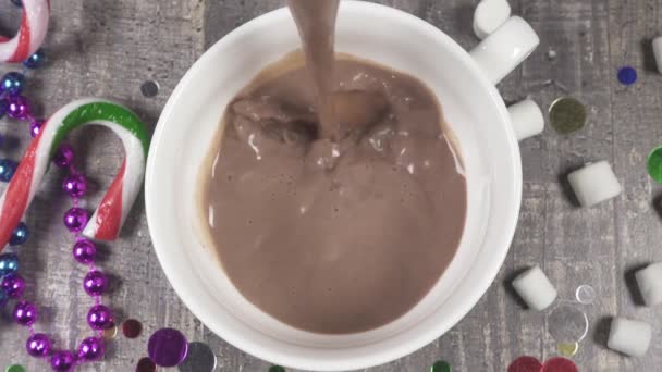 El chocolate caliente de cámara lenta se vierte en una taza cerca de los confeti y las cuentas de Año Nuevo vista superior — Vídeos de Stock