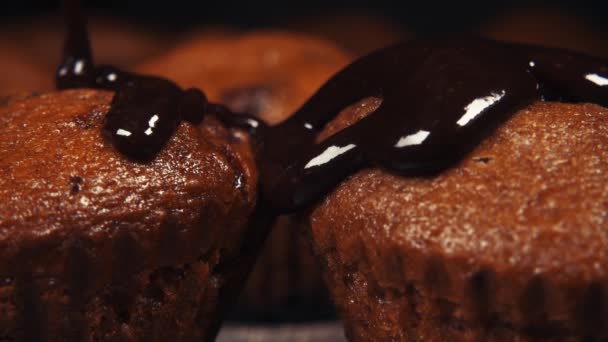 El glaseado de chocolate en cámara lenta vierte dos magdalenas de cerca — Vídeo de stock