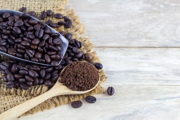 Coffee beans and coffee powder on wood table — Stock Photo, Image