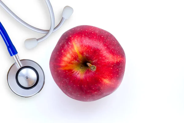 Chiuda il dettaglio di stetoscopio medico e mela rossa su un bianco — Foto Stock