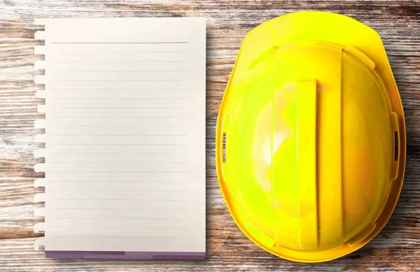 Visão superior do chapéu de capacete de segurança amarelo e papel em branco no proj — Fotografia de Stock