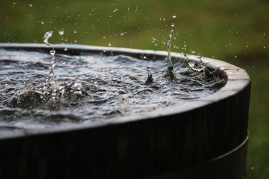 rain is falling in a wooden barrel full of water in the garden clipart