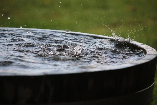 rain is falling in a wooden barrel full of water in the garden