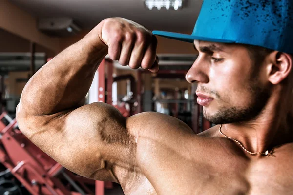 Bodybuilder Mit Blauer Mütze Schaut Auf Seinen Bizeps — Stockfoto