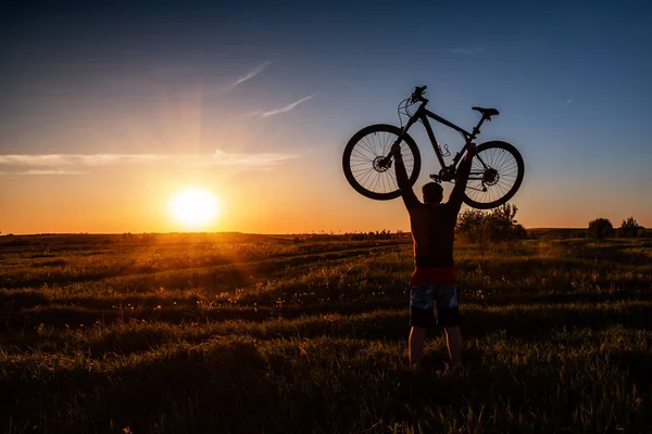 Silueta Hombre Pie Acción Levantando Bicicleta Por Encima Cabeza Prado — Foto de Stock