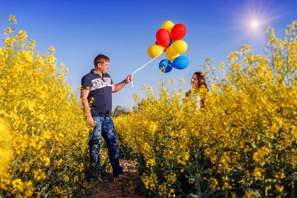 man, balloons and happy girl in blooming rape field