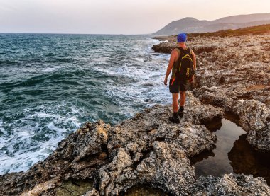kayalık sahil üzerinde sırt çantası duran adamla