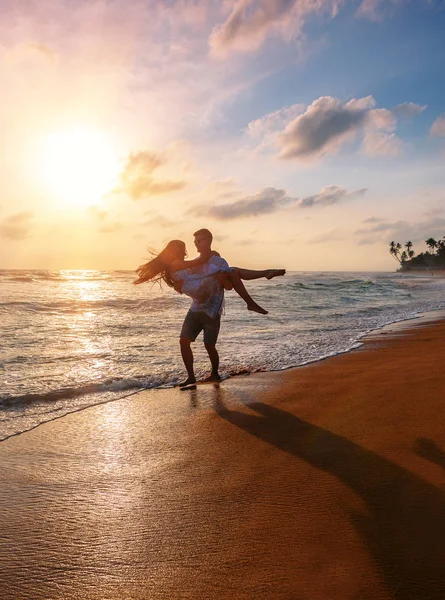 Man Houdt Het Meisje Haar Armen Het Strand Zonsondergang — Stockfoto