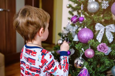 Sevimli küçük bir çocuk Noel ağacını süslüyor. Noel dekoru, yeni yıl. Noel havası. Tatillerde. Samimi. Küçük çocuk..