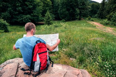 Haritalı ve kırmızı sırt çantalı bir yürüyüşçü